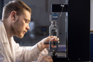 Expert performing a seal strength test on a test sample.